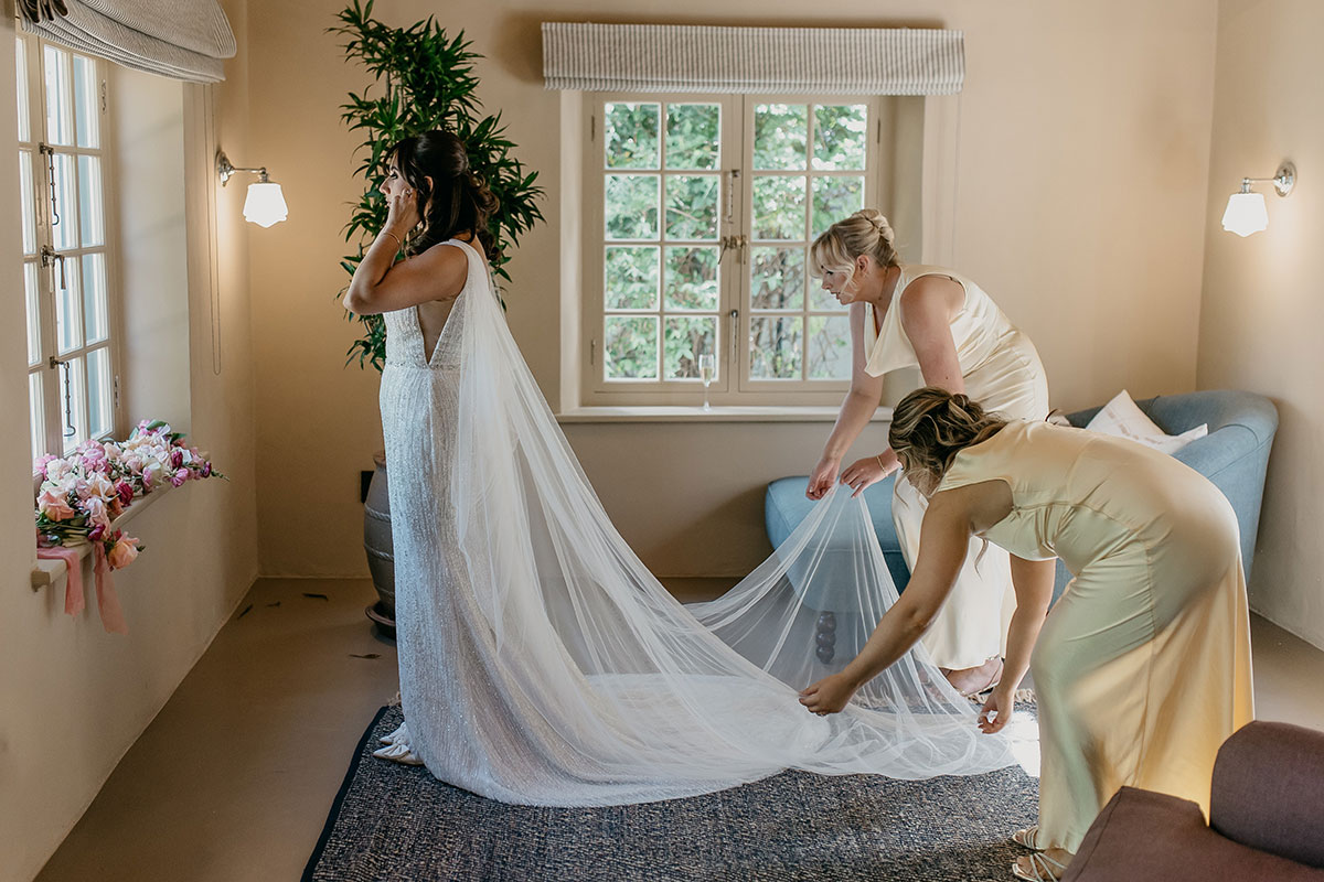 Bridesmaids helping the bride arrange her cathedral veil before the ceremony at Boschendal Wine Estate, South Africa
