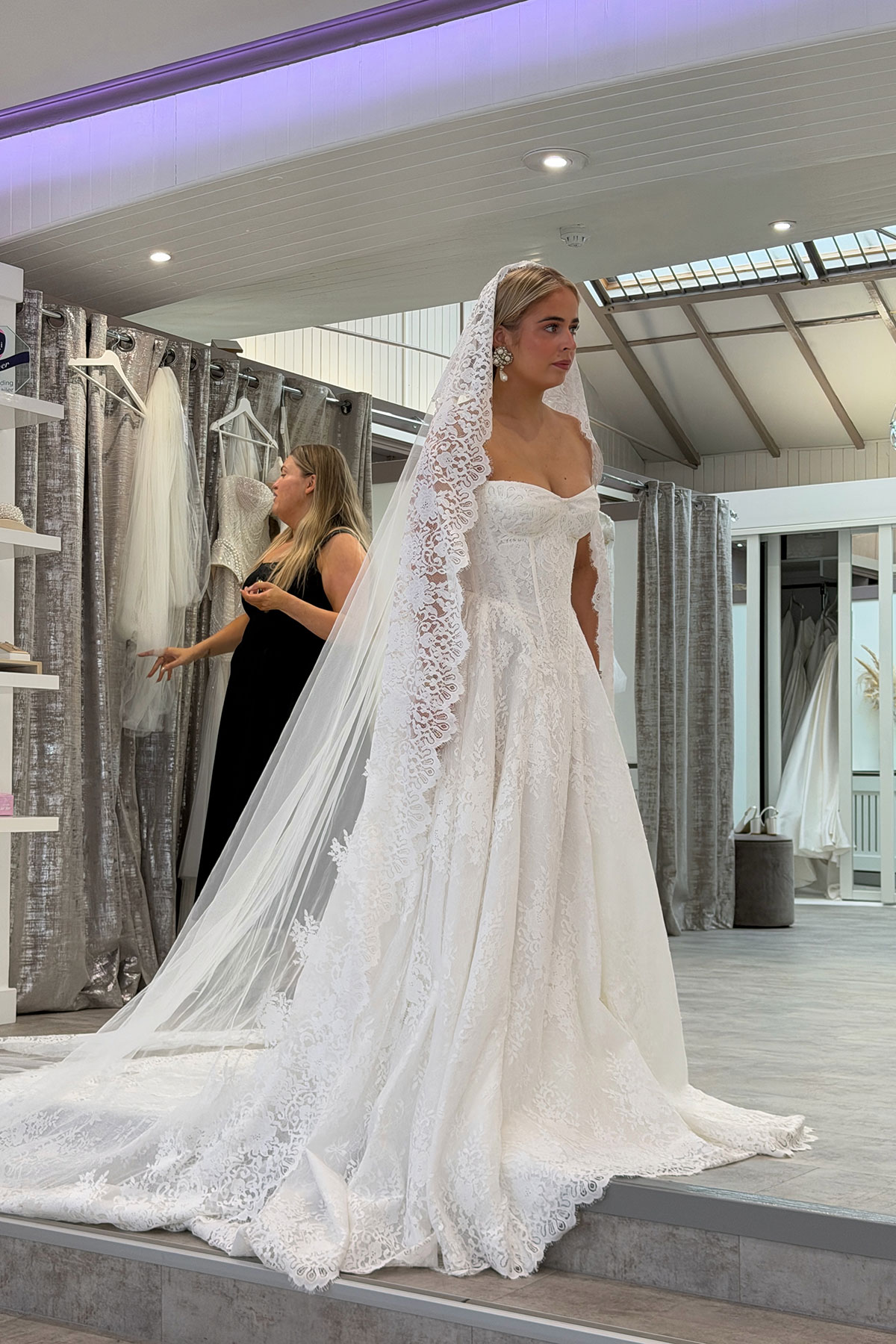 Ruby McFarlane trying on a lace wedding dress with a long lace-edged veil during a bridal boutique appointment.