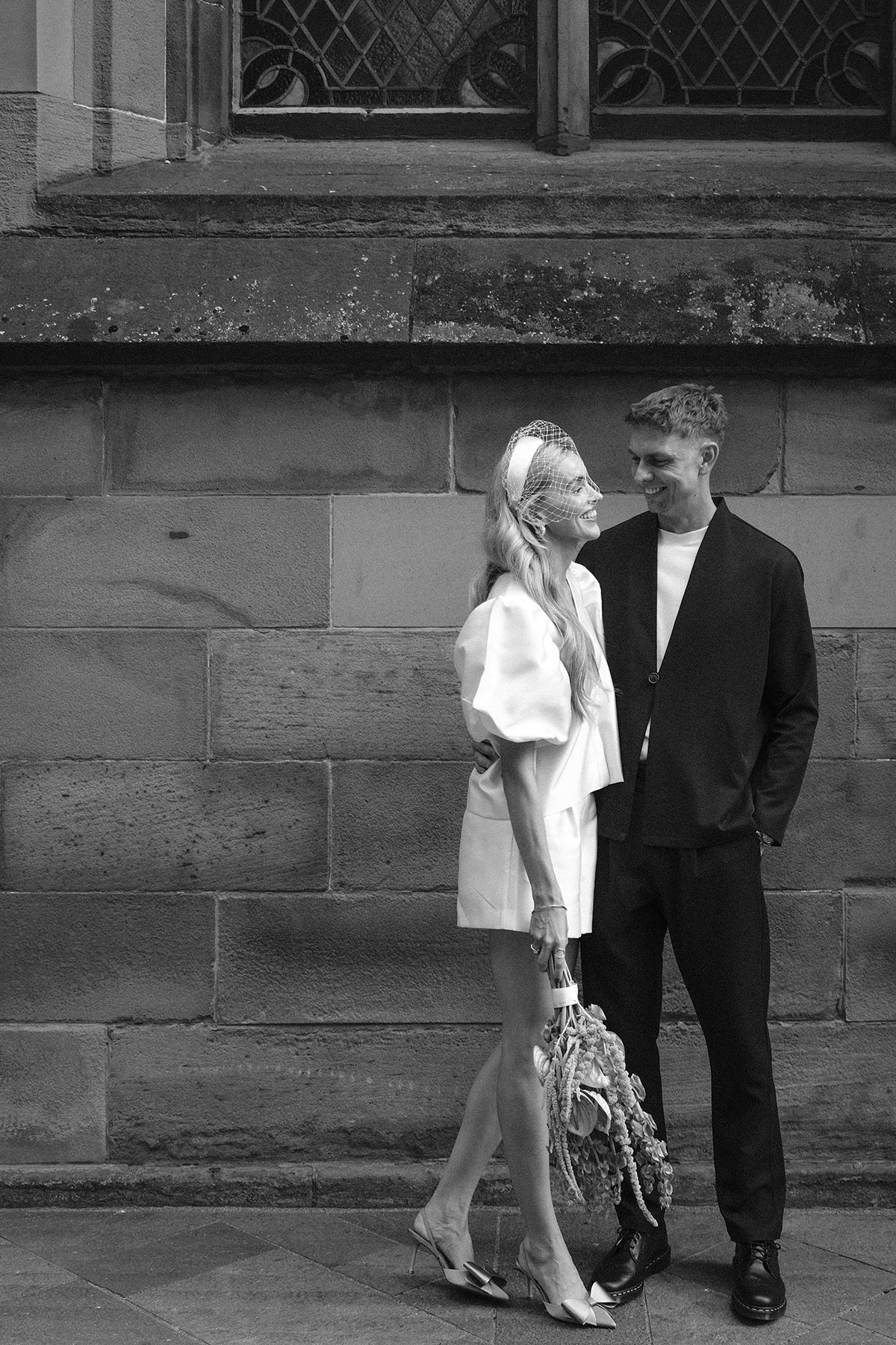 Bride and groom after Glasgow legal ceremony posing outside St Andrew’s Cathedral in modern wedding outfits