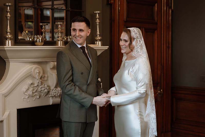 Newlyweds holding hands during their wedding ceremony at 23 Montrose Street in Glasgow.