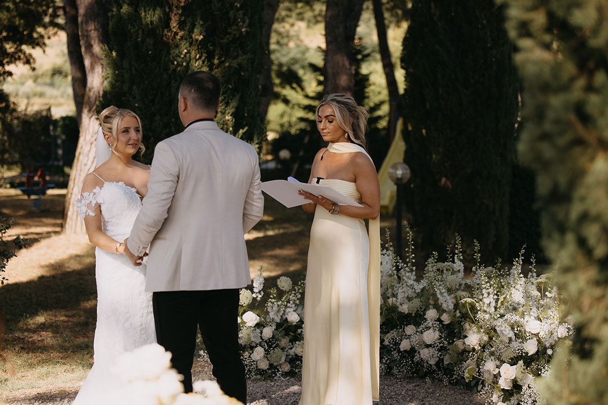 Outdoor wedding ceremony with bridesmaid doing wedding at Antico Borgo San Lorenzo Tuscany