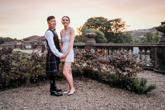 bride wearing short embellished dress holds hands with groom wearing kilt during sunset at mar hall