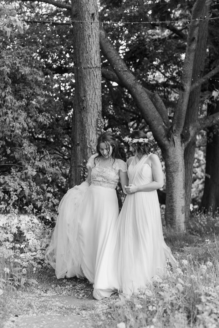 two brides walking hand in hand through a woodland at the Byre at Inchyra