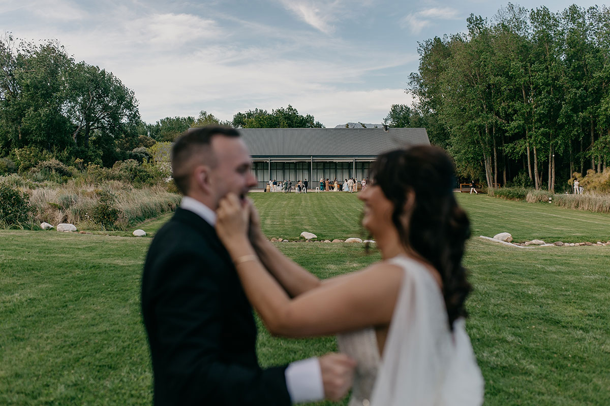 Bride laughing as she touches groom's face outside Boschendal Wine Estate following their South Africa destination wedding ceremony