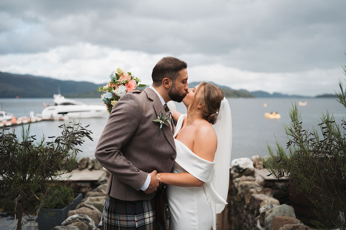 Bride and groom kissing beside Loch Lomond after their wedding at Lodge on Loch Lomond