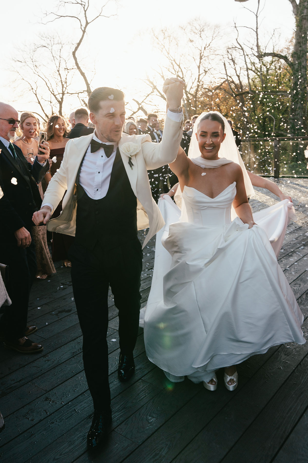 Newlyweds walking through confetti at Enterkine Country House wedding in Ayrshire surrounded by cheering guests
