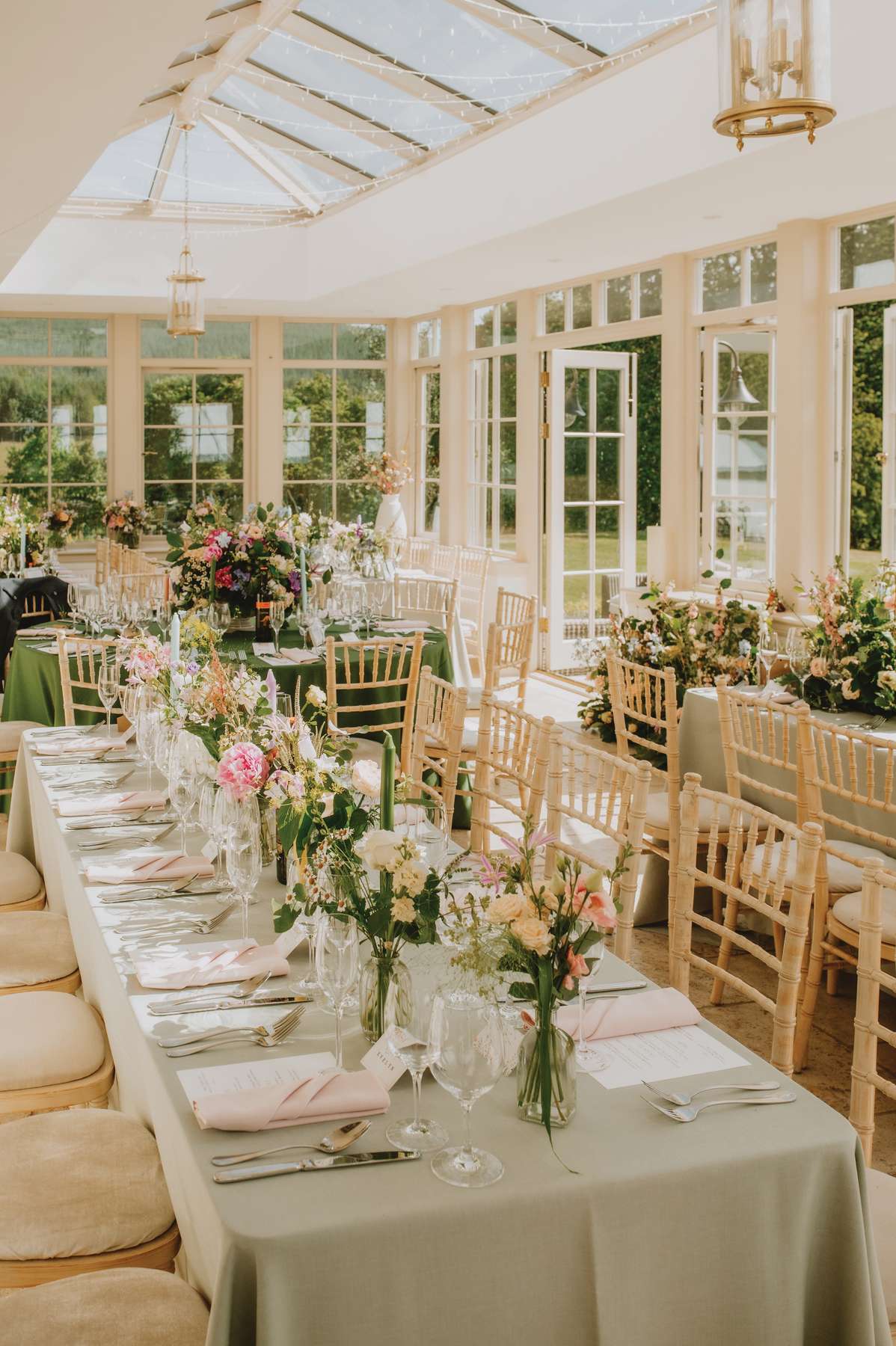 Sunlit conservatory wedding reception at Ballogie House with floral table styling and glass roof