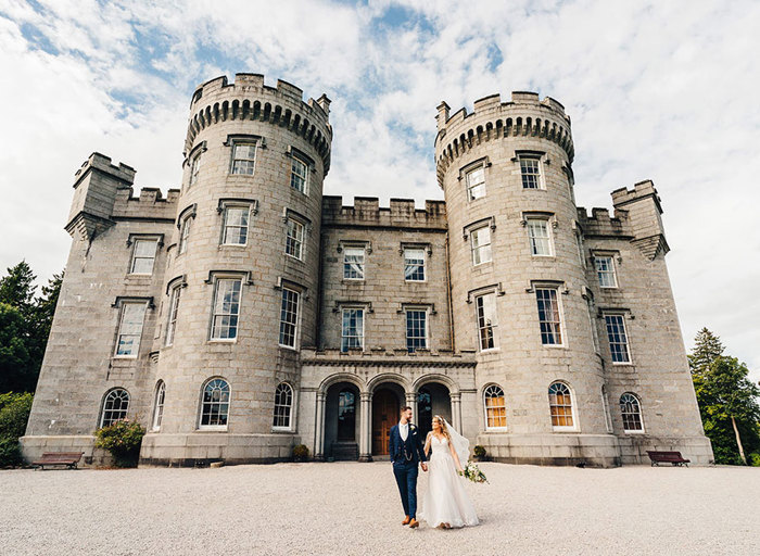 Bride and groom stand outside the grandeur of Cluny Castle