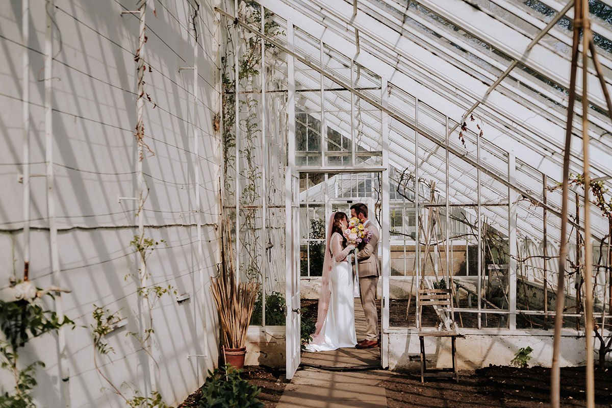 a bride and groom posing in a glasshouse at Carlowrie Castle