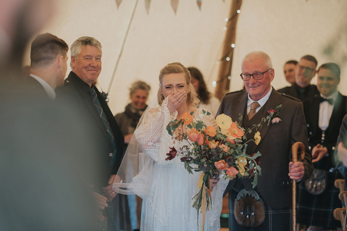 The bride is emotional as she walks the aisle with her father