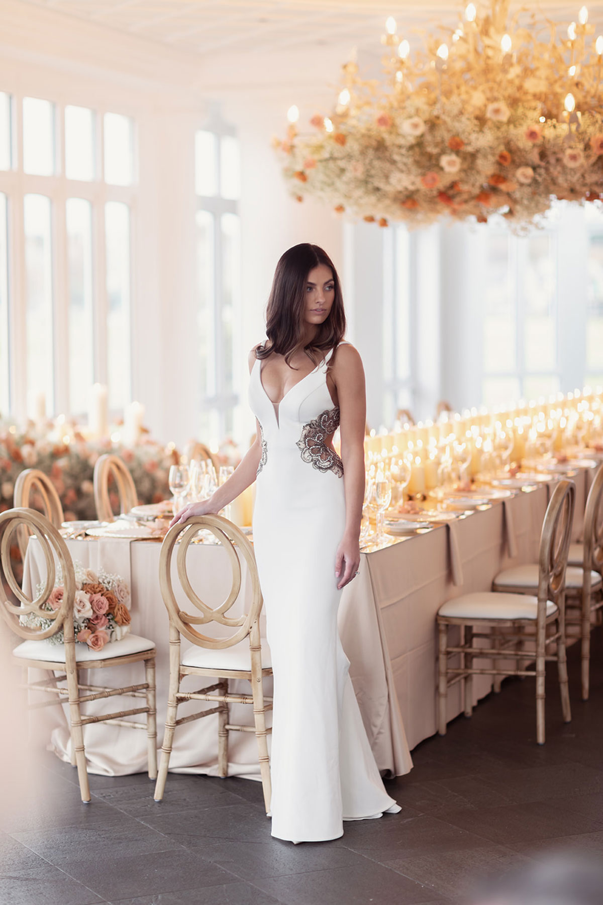 Bride standing by reception table in Old Course Hotel Conservatory, St Andrews, with floral chandelier overhead