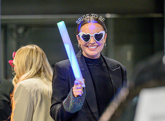 A woman wearing a 'bride to be' headband and holding a glowstick 