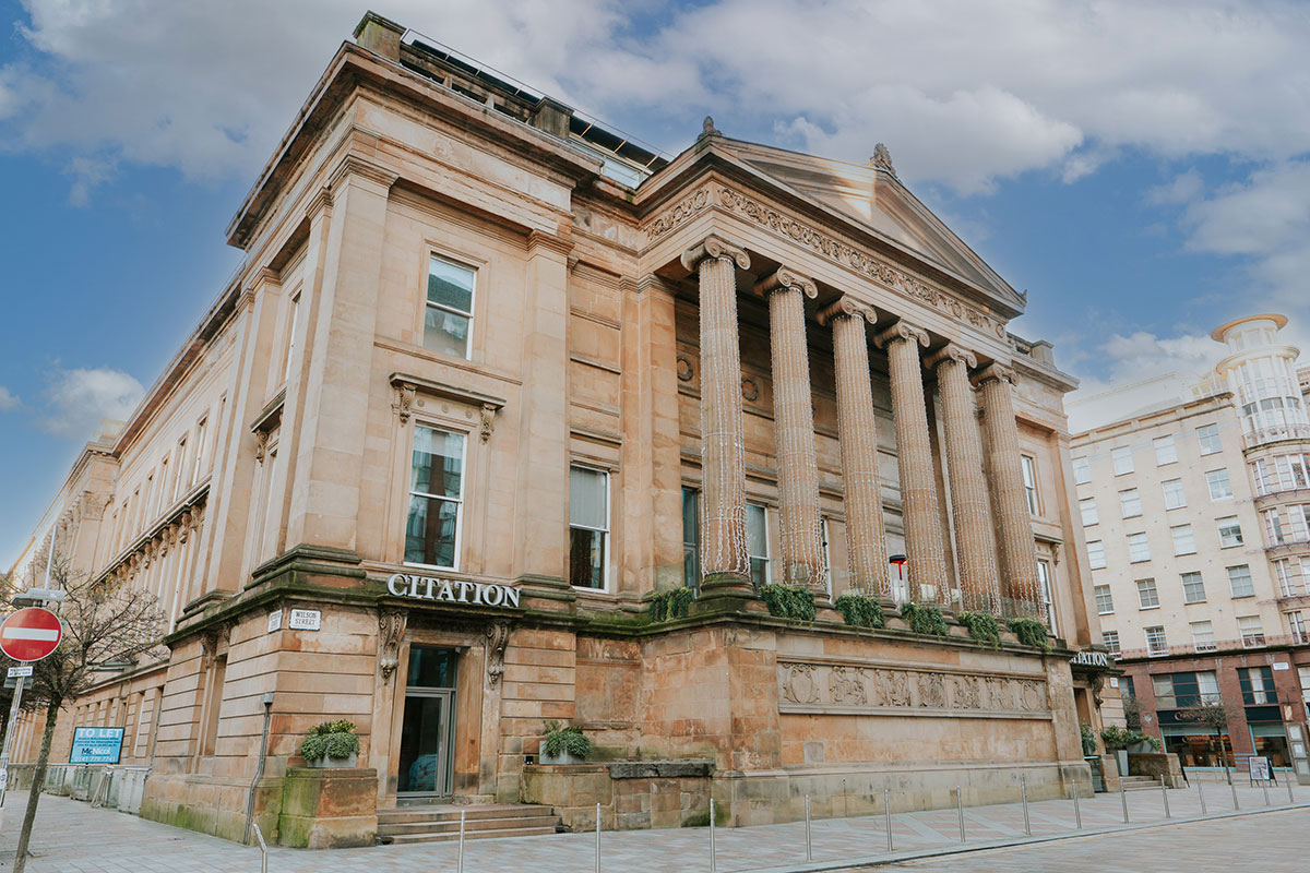 the outside of sandstone coloured building with tall Greek columns and a sign over the entrance that says 'Citation'