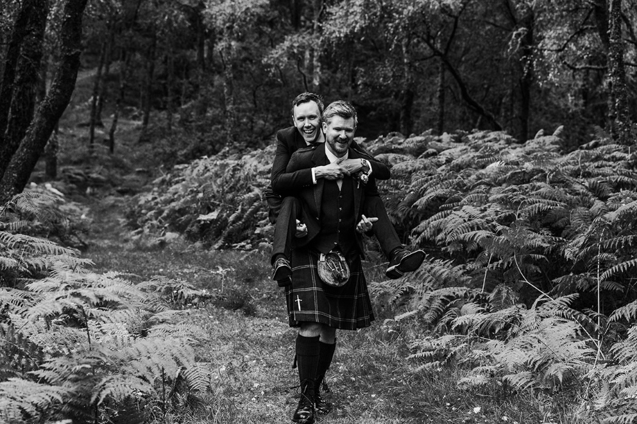 Black and white image of groom giving the other a piggy back