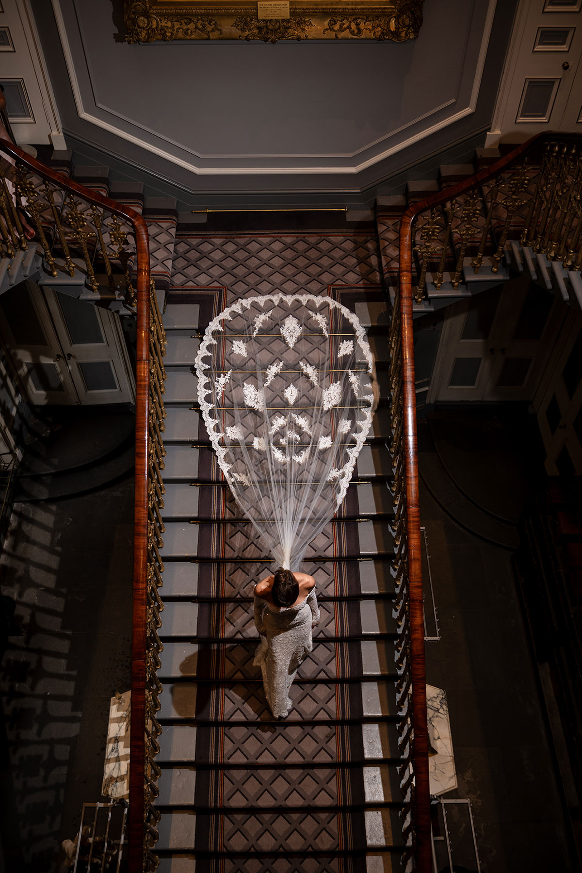 Overhead shot of bride’s lace veil spread across Signet Library staircase
