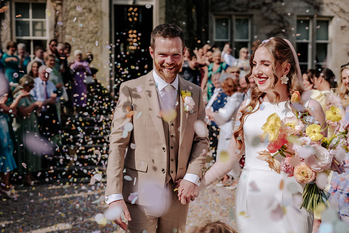 a bride and groom being showered in confetti outside Carlowrie Castle Edinburgh wedding venue