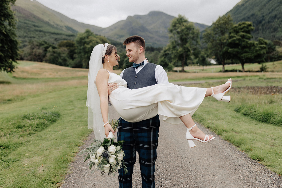 Groom picking up the bride, mountains in the background
