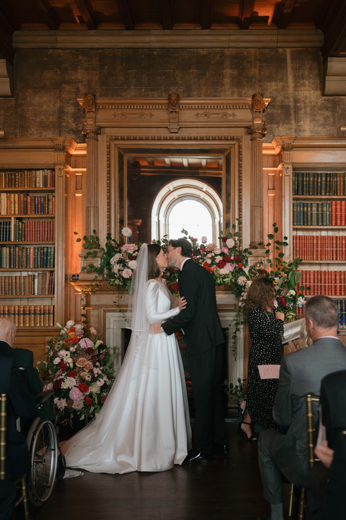 Newlyweds Nicole and Ryan share their first kiss during their wedding ceremony in the flower-filled library at Barnbougle Castle.