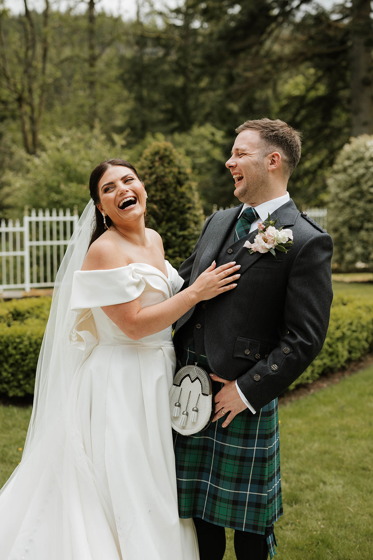Bride and groom laughing together in Drumtochty Castle gardens Aberdeenshire after ceremony