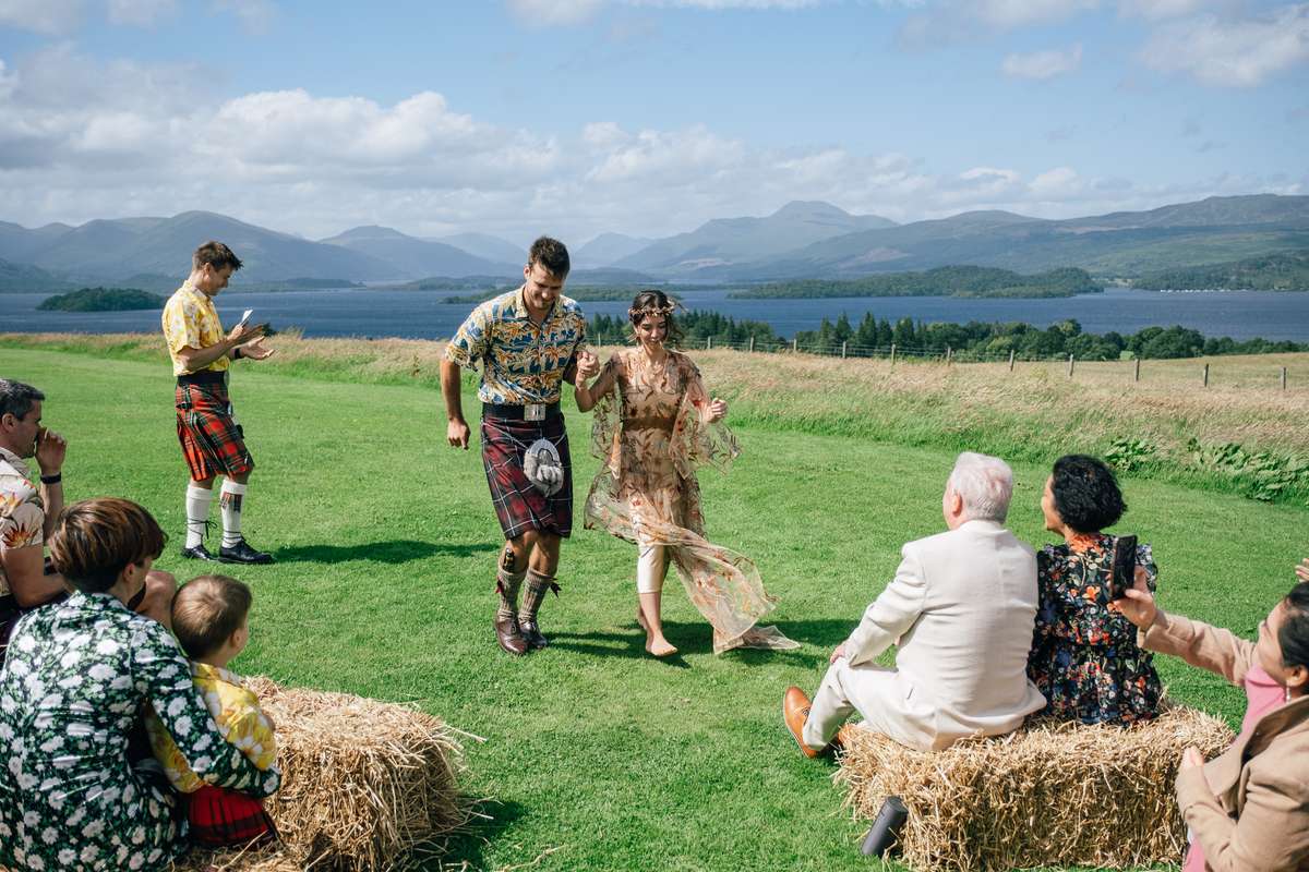 Newlyweds walking through their guests following an outdoor ceremony at Ardoch Loch Lomond