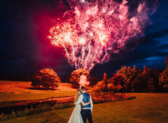 The newly-weds watch a red and purple display of fireworks go off in the night sky