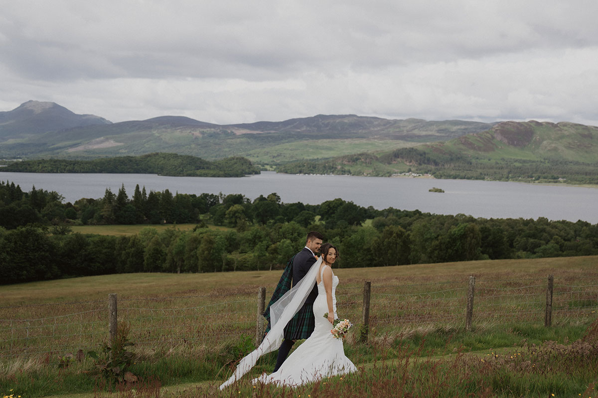 romantic couple portrait overlooking Scottish loch landscape with dramatic cloudy skies