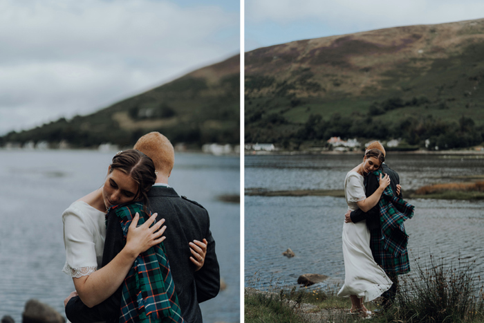 Bride and groom embrace at the edge of a loch