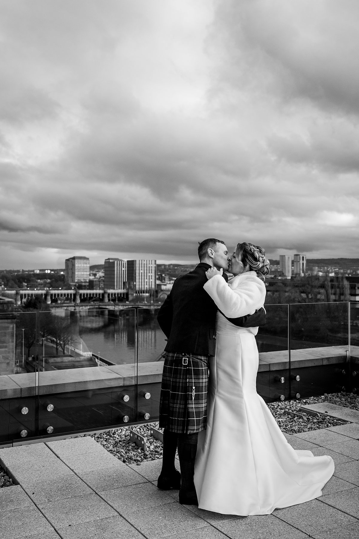 Bride and groom share a kiss on the rooftop terrace at Clayton Hotel Glasgow with views over the city.