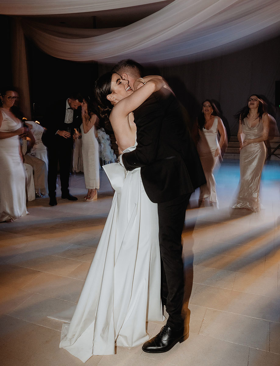 A couple in formal attire embraces on a dance floor