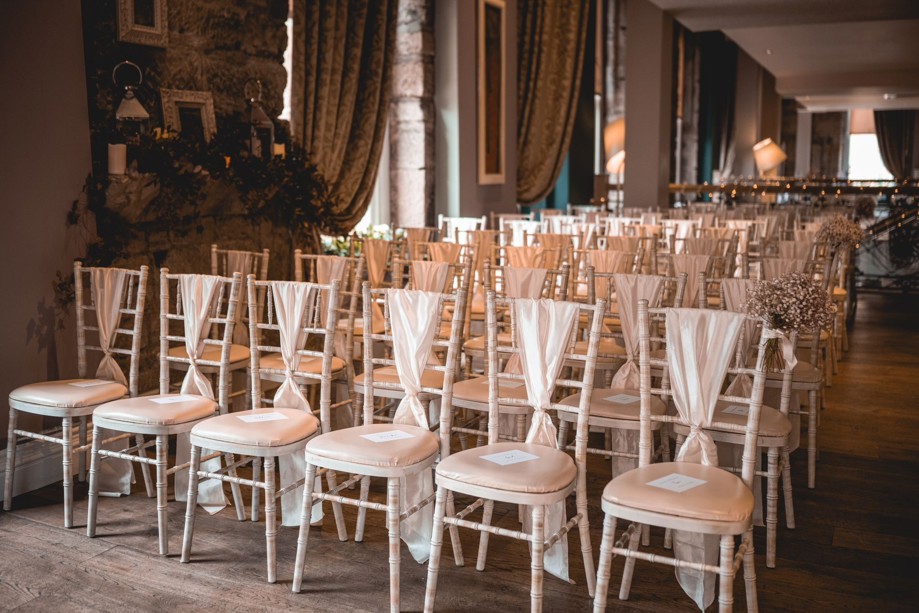 Rows of Chiavari chairs in Citation Glasgow set up for a wedding ceremony with ivory tiebacks and gypsophila on ends of chairs