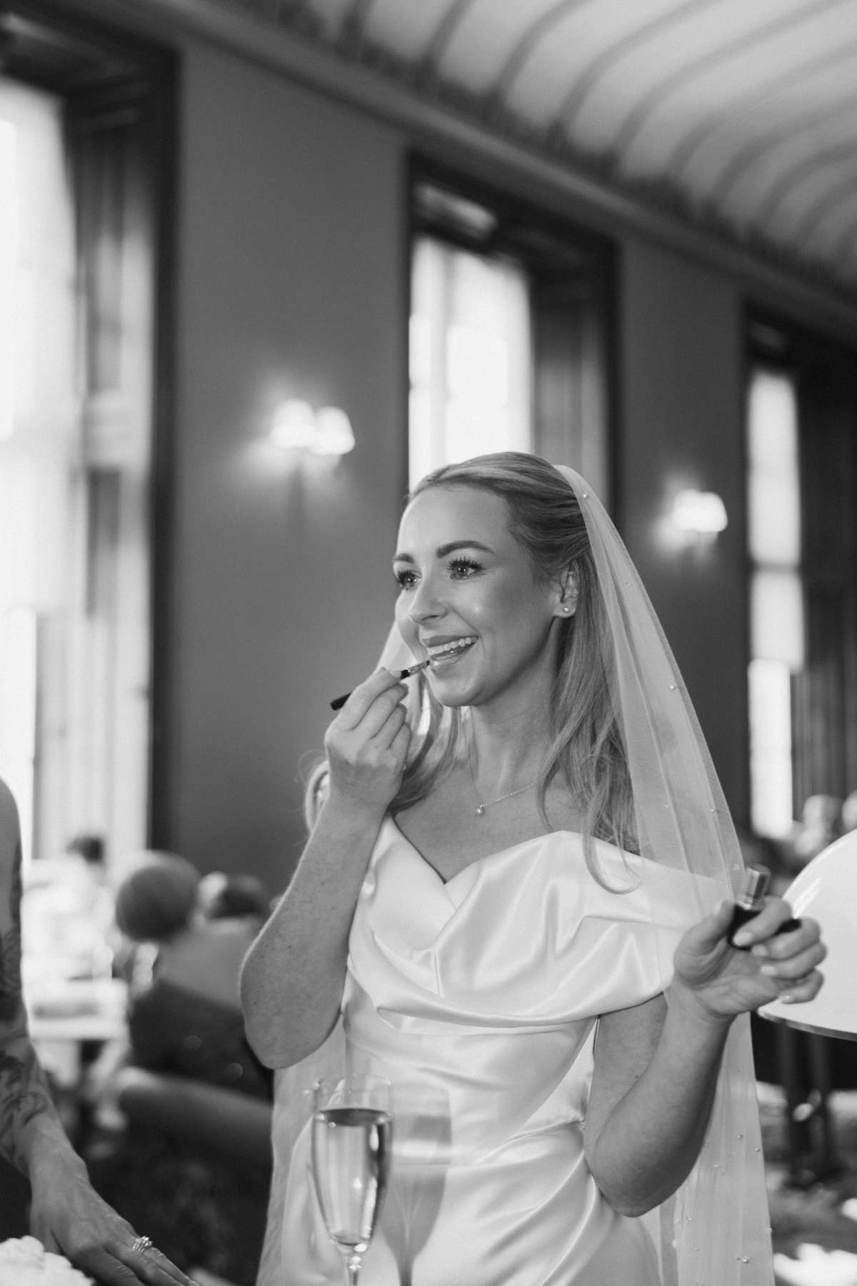 Bride Siân applies lipstick during her Mar Hall wedding reception, wearing a Vivienne Westwood Nova Cocotte wedding dress.