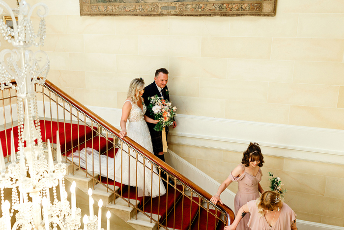 Bride and father walk down the stairs before ceremony 