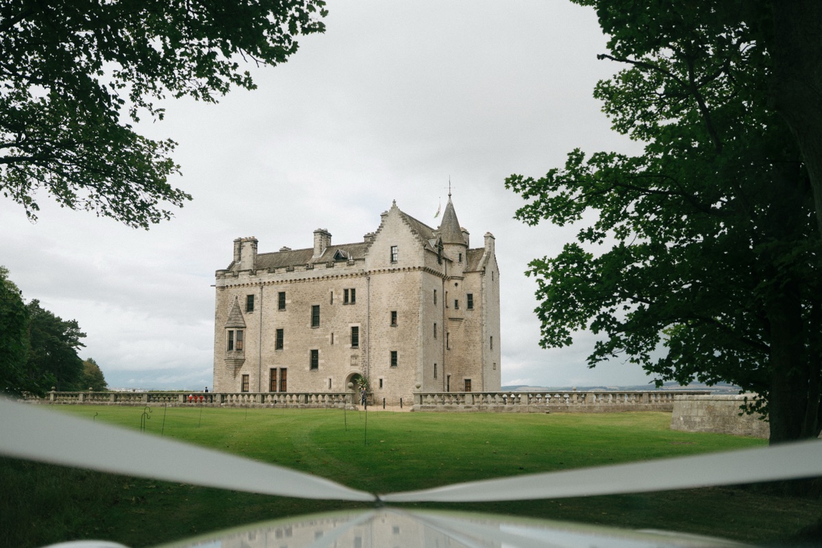 Exterior of Barnbougle Castle, a historic waterfront wedding venue in South Queensferry near Edinburgh, framed by trees and lawns.