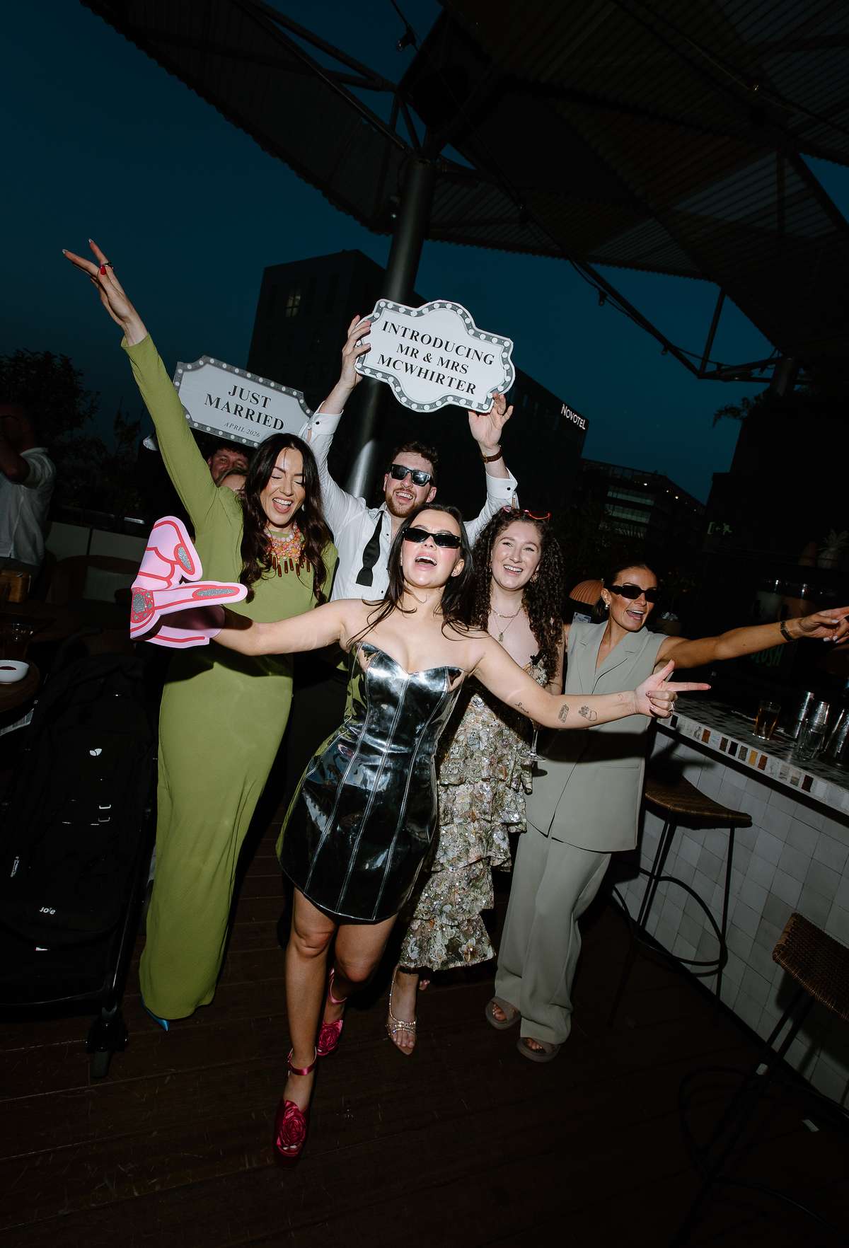 Bride in a metallic silver mini dress celebrates with friends during the rooftop wedding party at The Hoxton Barcelona.
