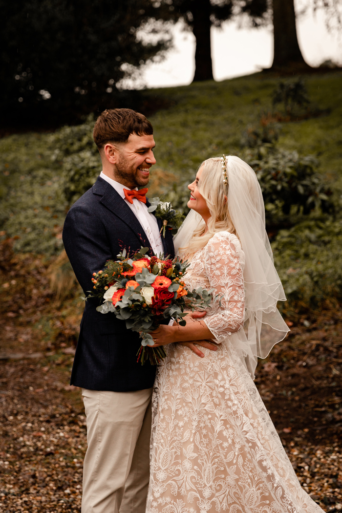 bride and groom smiling orange accessories and flowers