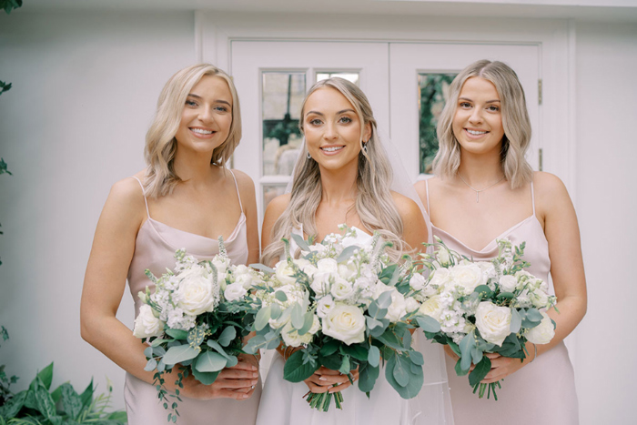 Bride and two bridesmaids wearing pink gowns all holding bouquets 