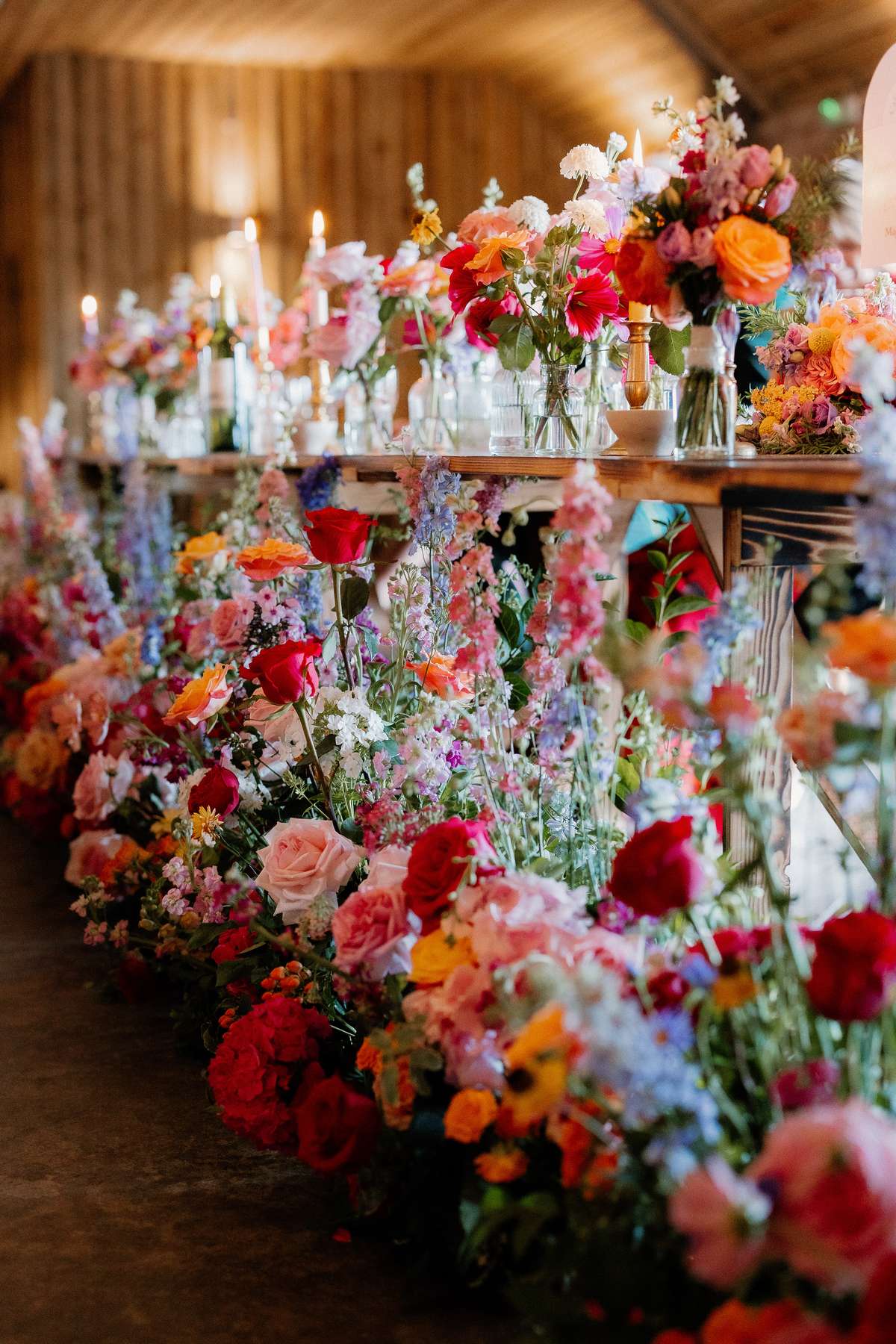Abundant colourful floral tablescape with candles decorating the wedding reception at Falside Mill