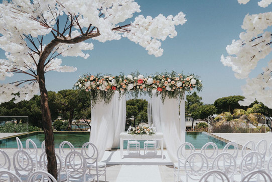 a white wedding ceremony set up outside with blossom trees at Quinta do Lago Portugal