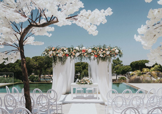 a white wedding ceremony set up outside with blossom trees at Quinta do Lago Portugal