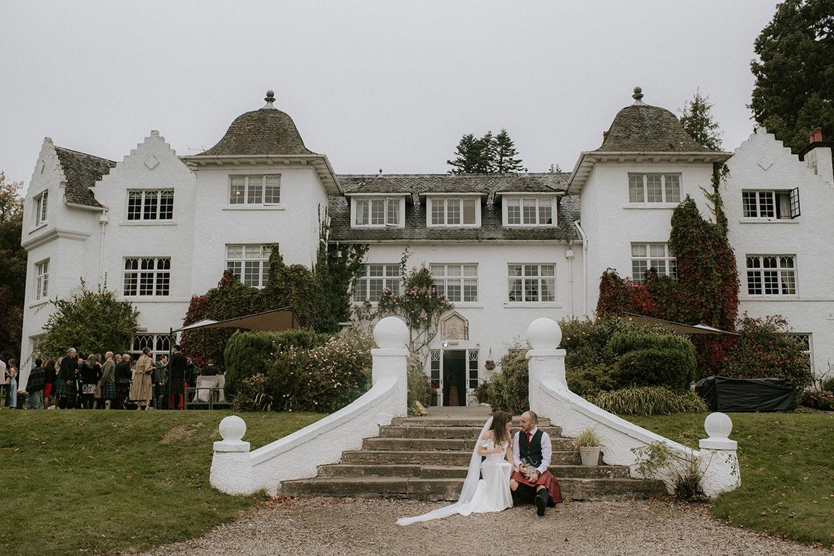 a bride and groom seated on stone staircase outside Achnagairn Castle