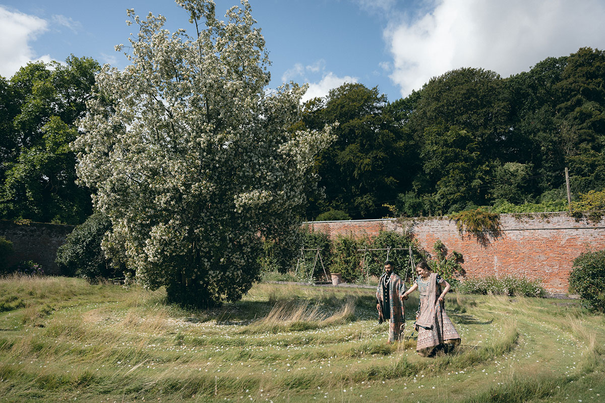 A bride and groom wearing Indian attire walking in the walled garden at Byre of Inchyra.