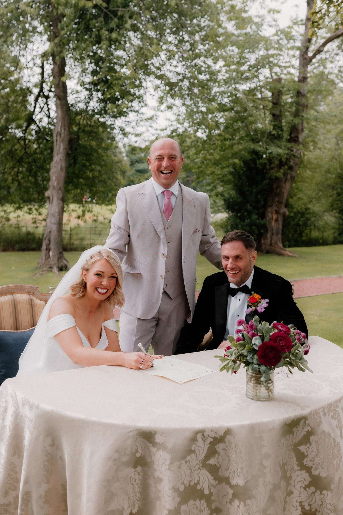 Bride Kara signs the wedding register alongside Rory after their outdoor ceremony at Prestonfield House in Edinburgh.