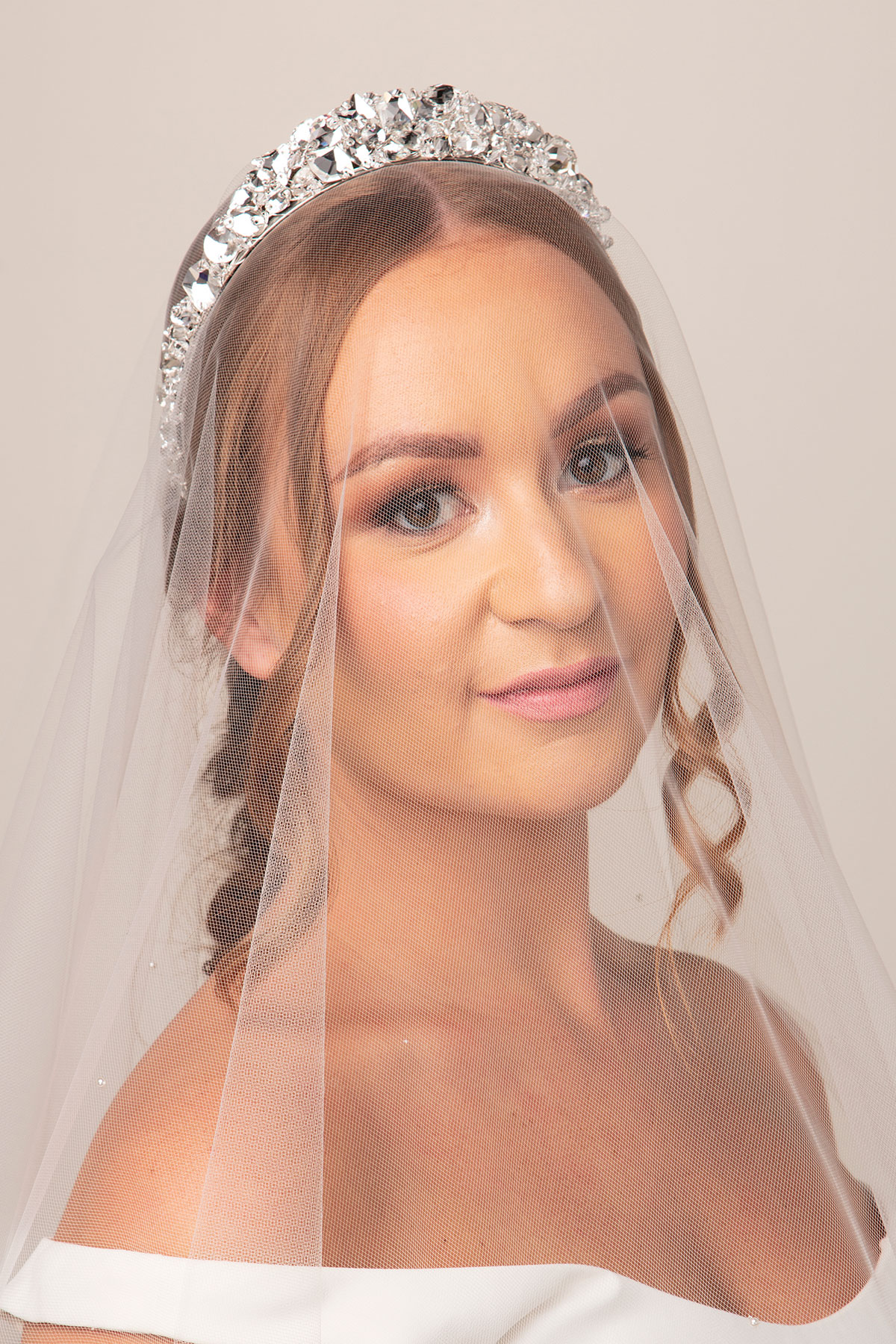 Bride wearing a crystal bridal tiara with a soft tulle wedding veil by Baba-C Designs.