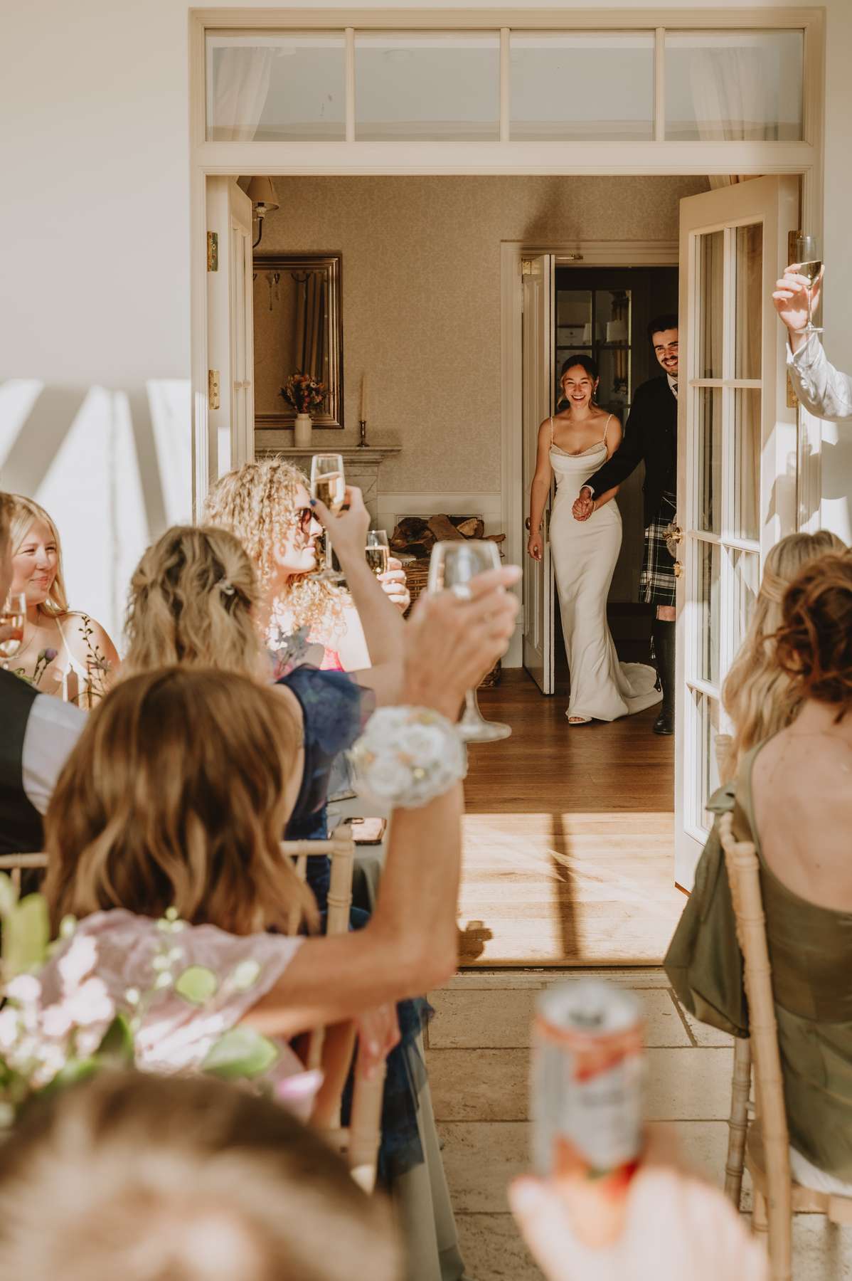 Newlyweds enter their Ballogie House wedding reception as guests raise glasses in celebration