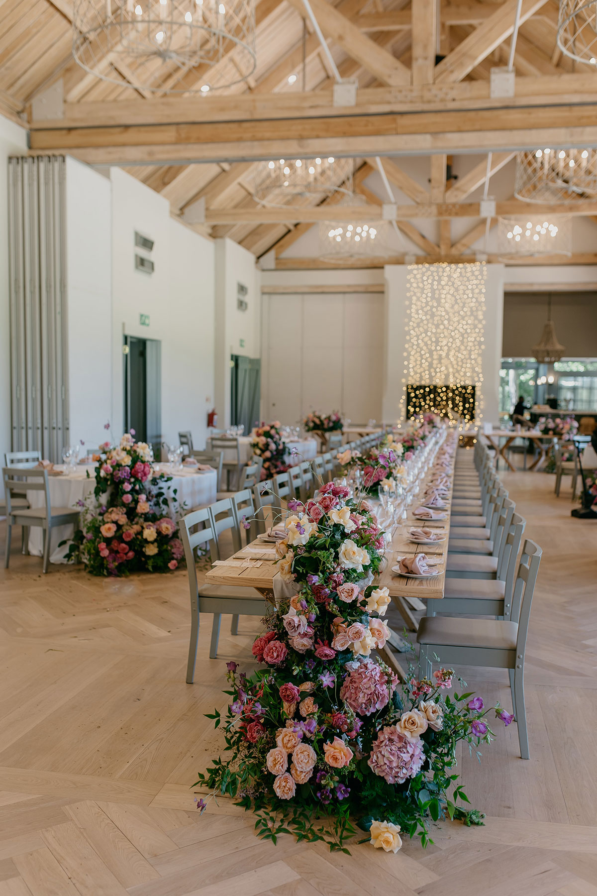 Long banquet tables with abundant pastel floral arrangements at Boschendal Wine Estate wedding reception in Cape Town