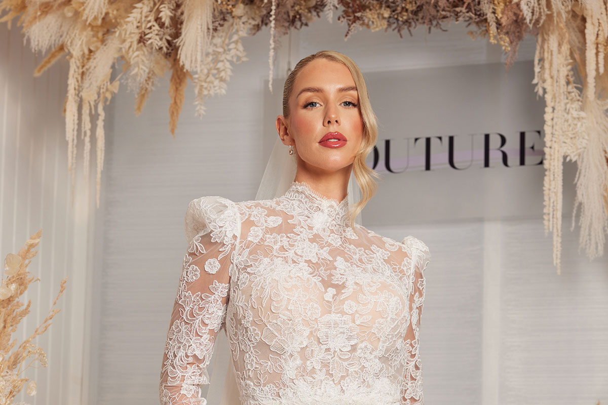landscape image of model and influencer romy mccahill wears a high neck lace dress from opus couture with a red lip and hair up