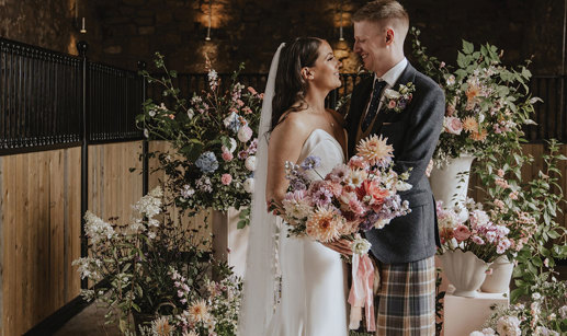 bride and groom smile with floral backdrop