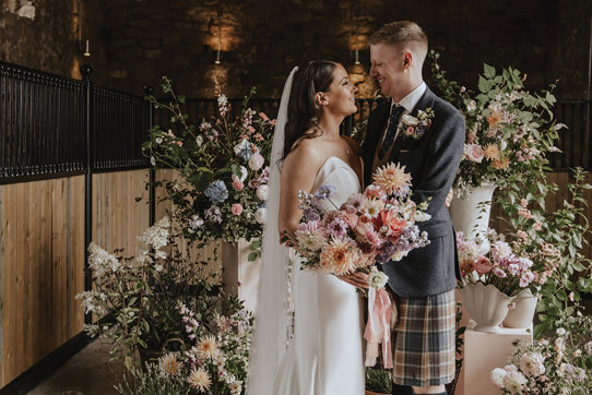 bride and groom smile with floral backdrop