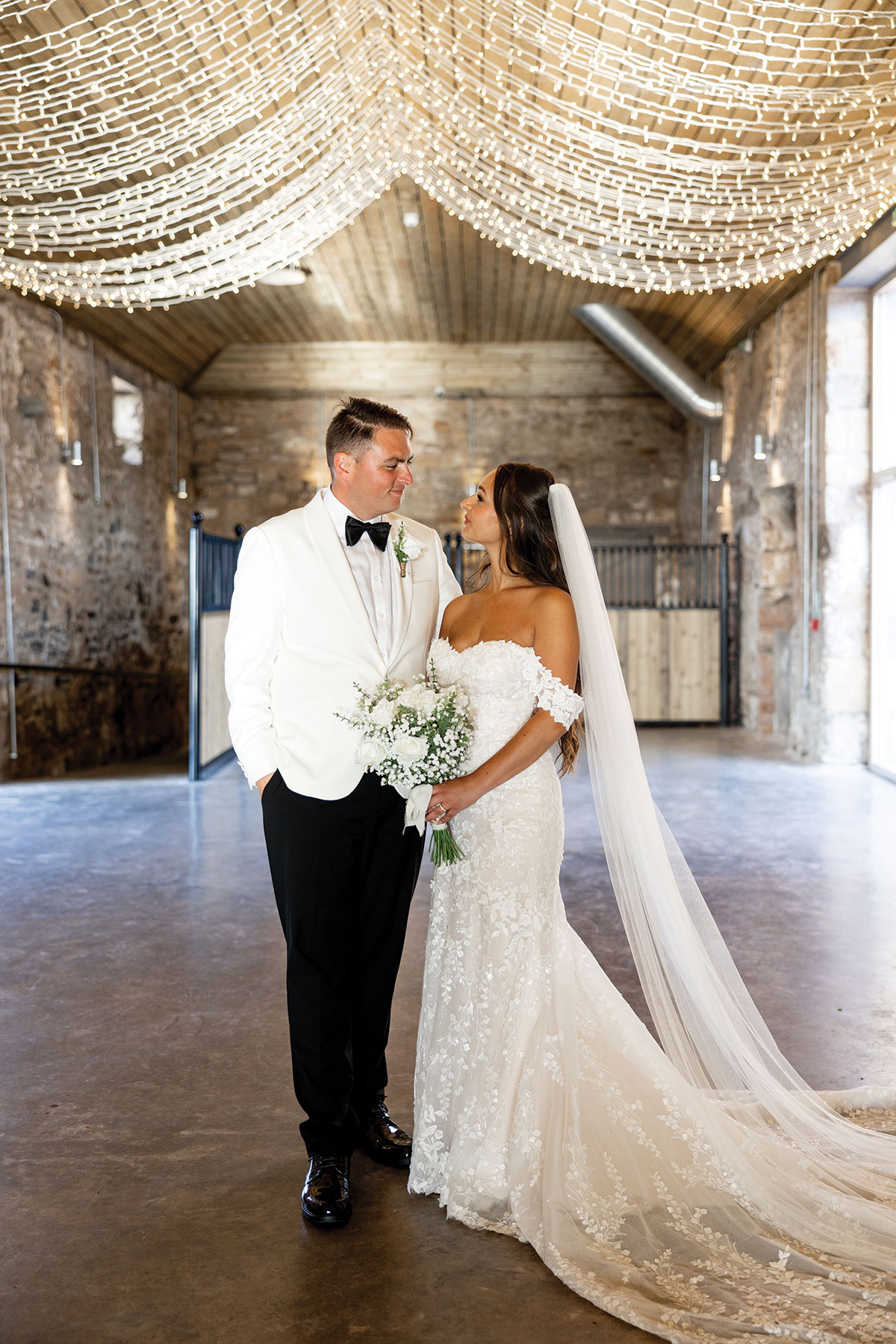 Newlyweds share a moment beneath twinkling fairy lights at their Falside Mill wedding in Fife.