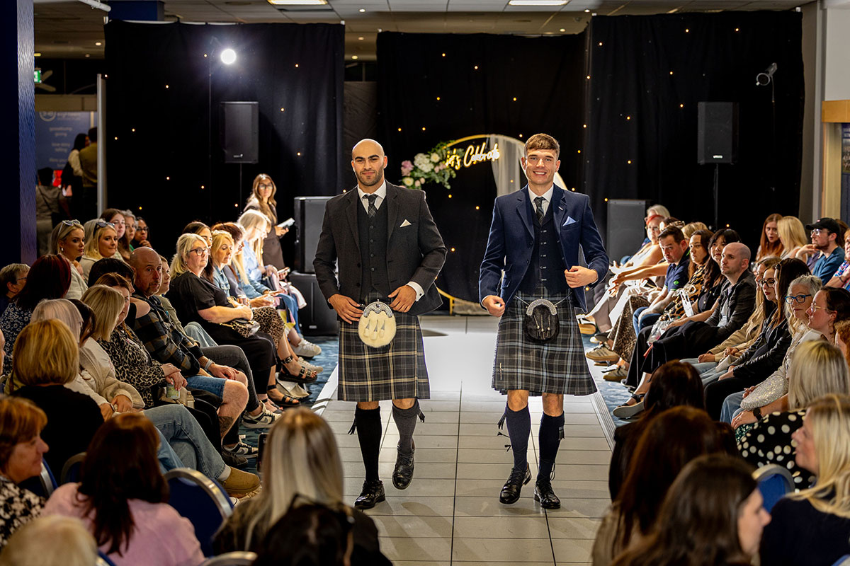 Two male models wearing kilt outfits walking down the catwalk at the Edinburgh Wedding Exhibition